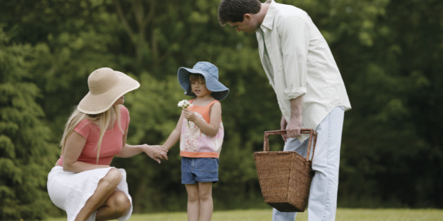 Homem, mulher e criança em ambiente externo e arborizado.