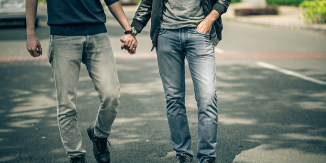 Dois homens caminham de mãos dadas. 