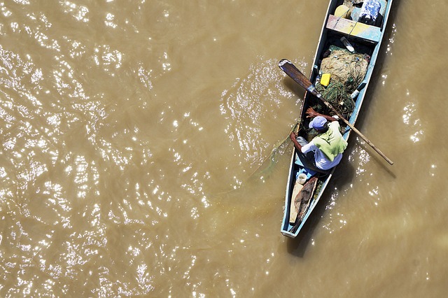 Homem em canoa sobre água suja