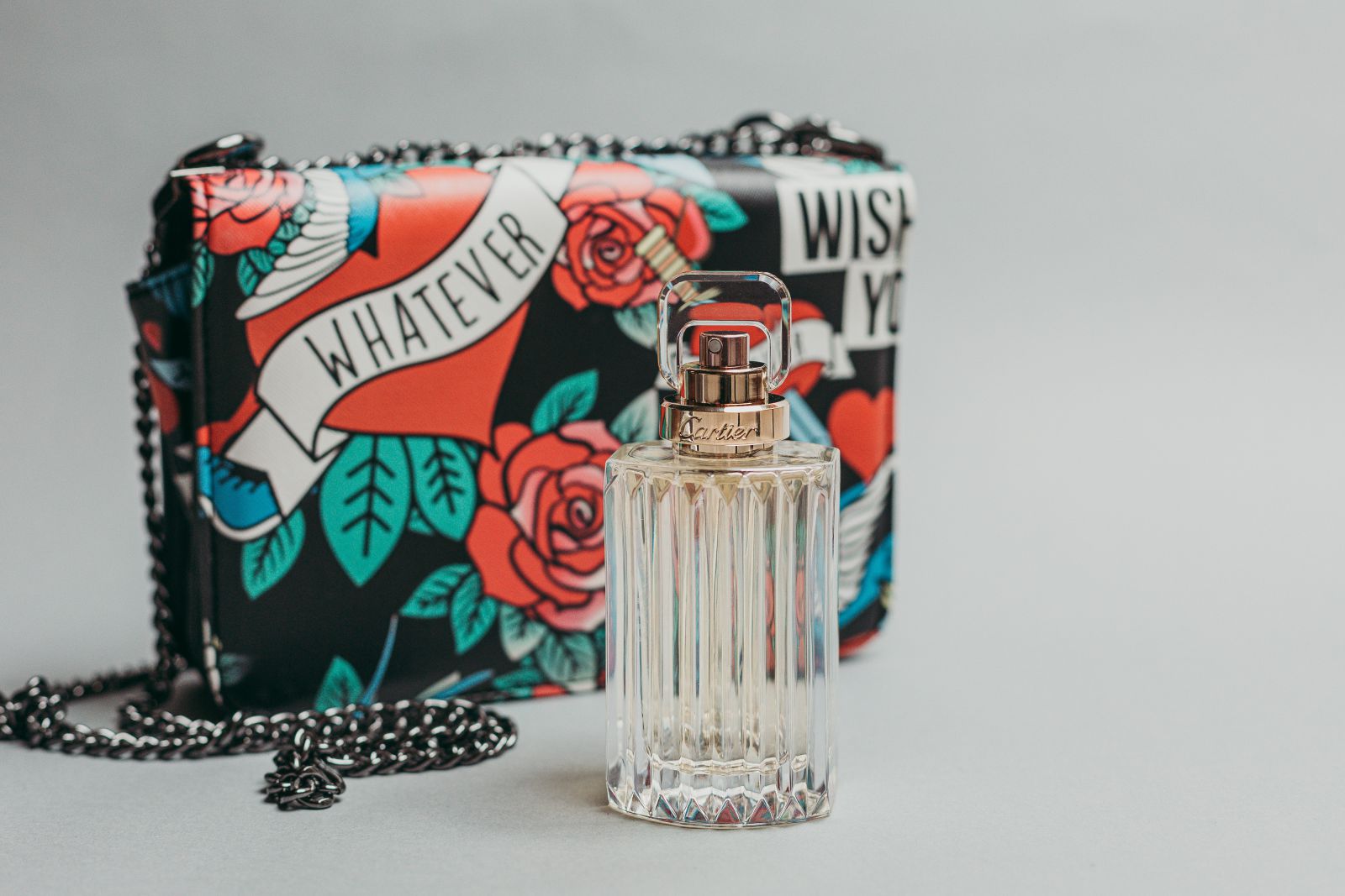 Frasco de perfume ao lado de uma bolsa