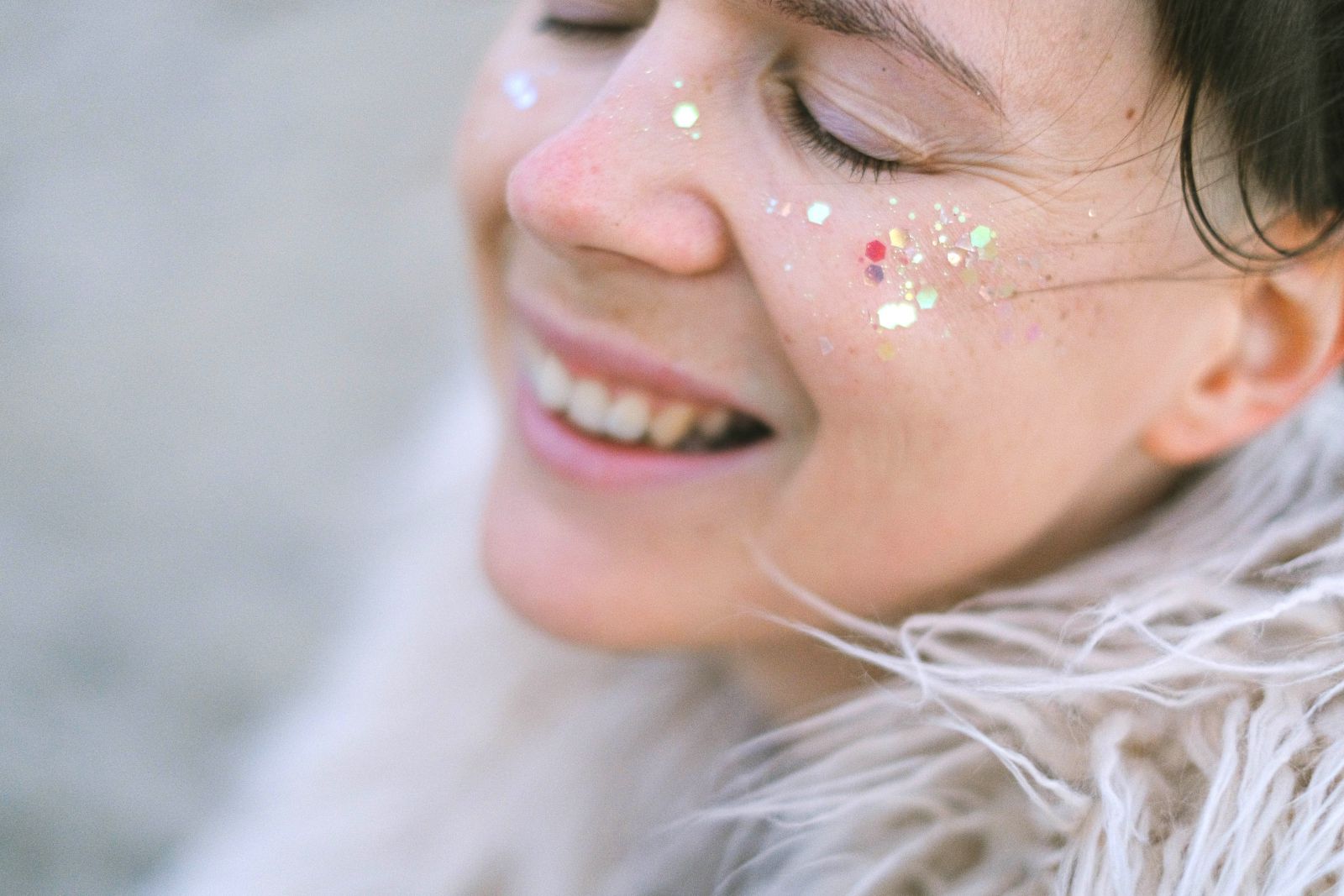 Pessoa sorrindo de olhos fechados com brilho no rosto