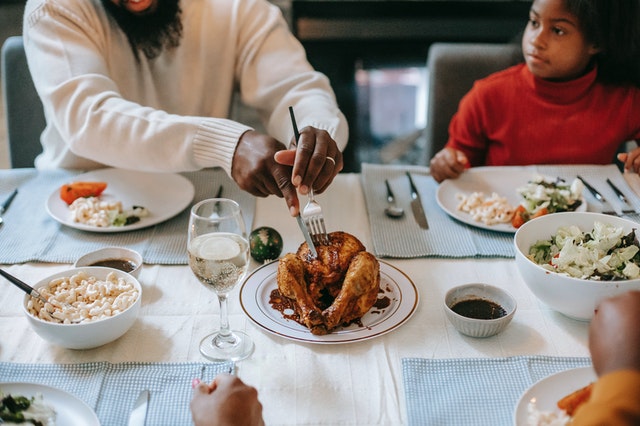 Homem cortando um frango de Natal em uma mesa toda arrumada