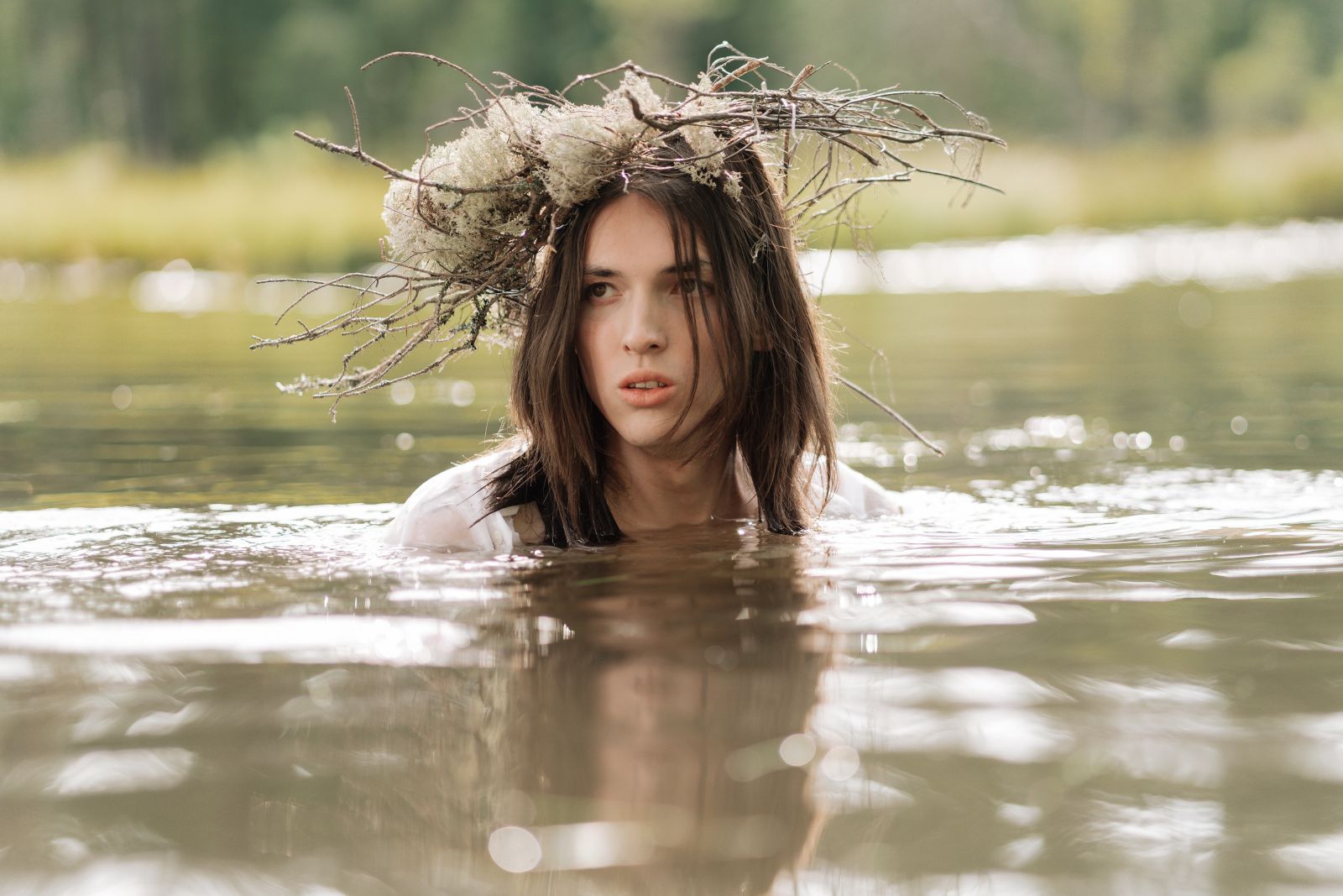 Mulher no mar com flores e galhos na cabeça