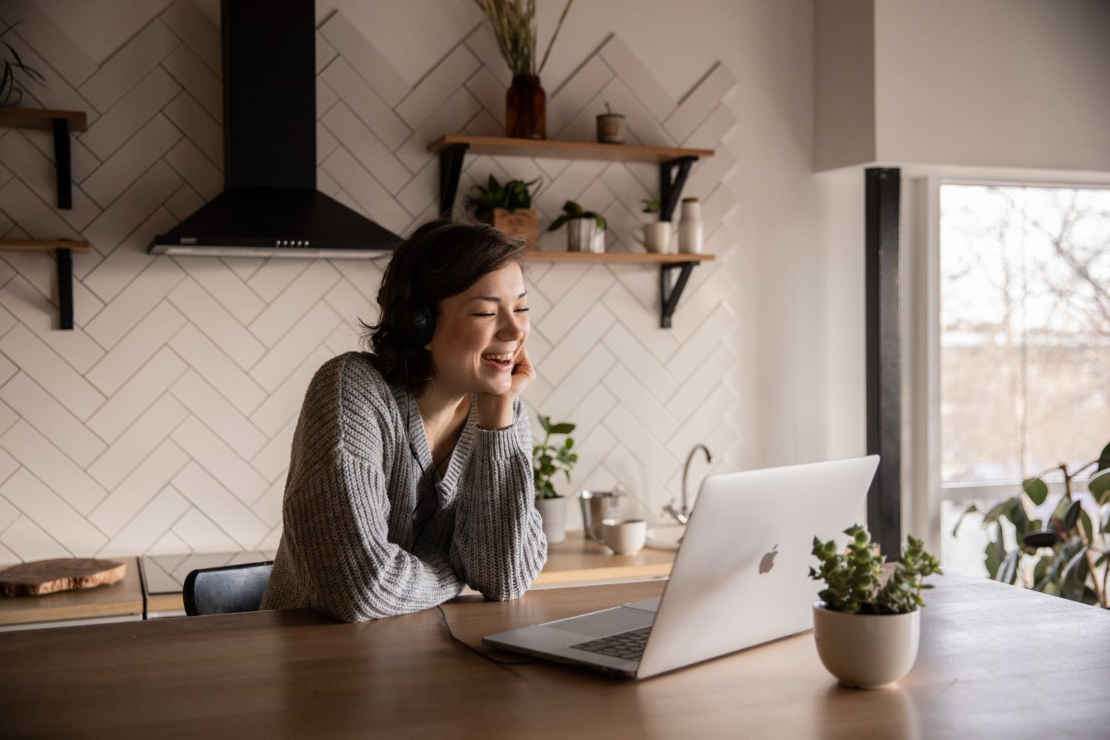 Mulher na cozinha sorrindo e olhando para o computador