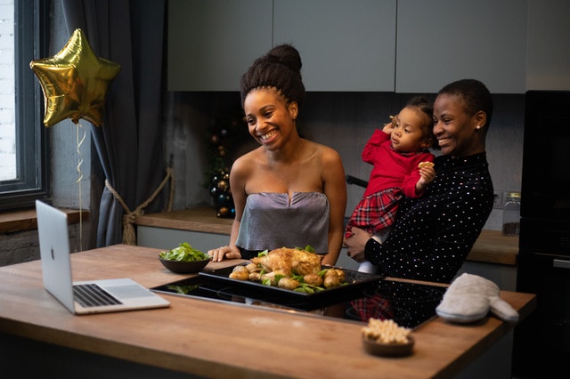 Duas mulheres olhando para o computador em frente a um balcão com comidas natalinas