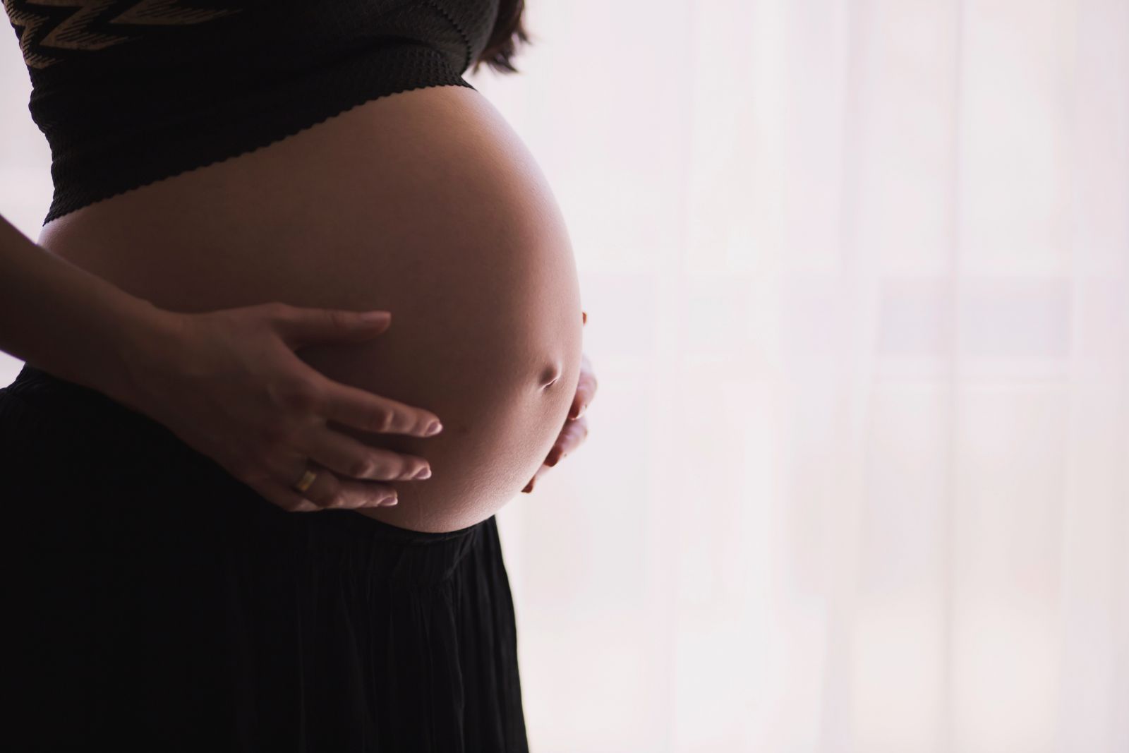 Mulher gravida com as mãos na barriga