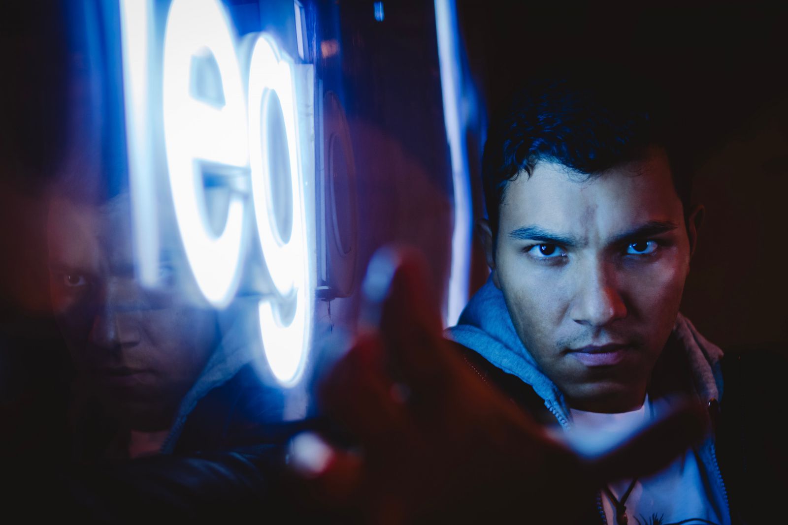 Homem olhando para frente ao lado de um letreiro iluminado