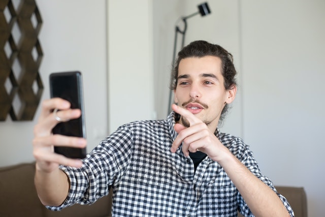 Kampus Production / Pexels Homem branco fazendo brincadeiras com o celular.