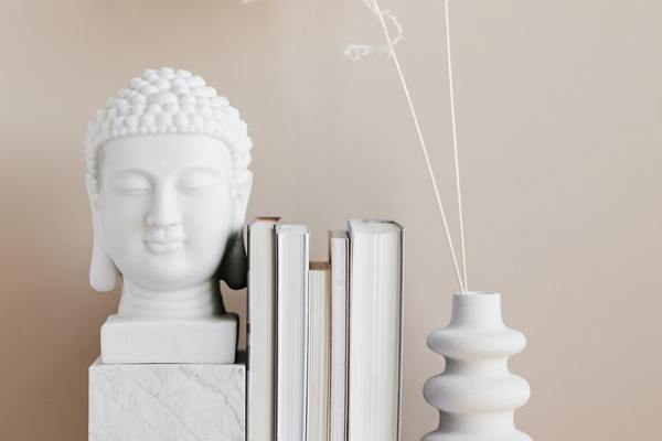 Escultura branca com livros ao lado.