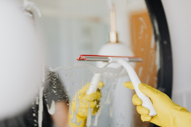 Mulher branca limpando espelho.