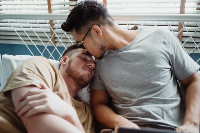 Homens brancos deitados numa cama.