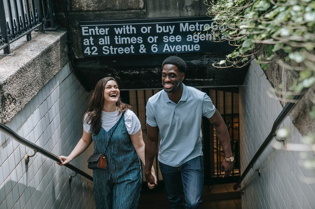 Homem negro e mulher branca sorrindo de mãos dadas.