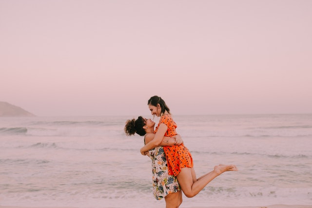 Mulheres brancas abraçadas na praia.