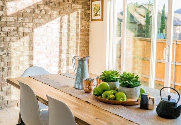 Mesa de madeira com o sol invadindo pelas janelas ao fundo