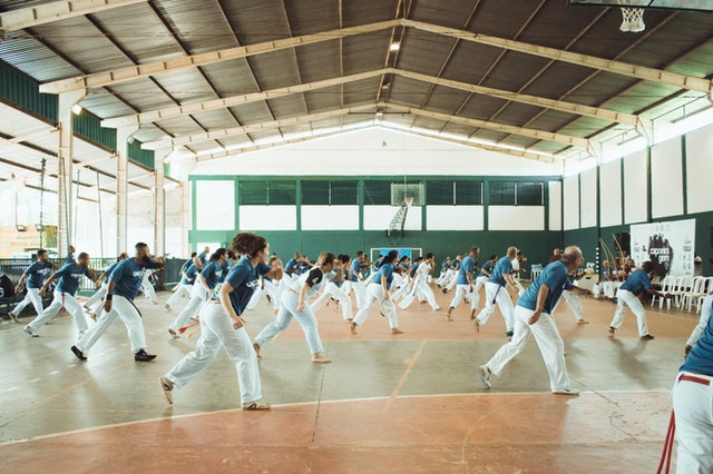 Pessoas praticando capoeira numa quadra.