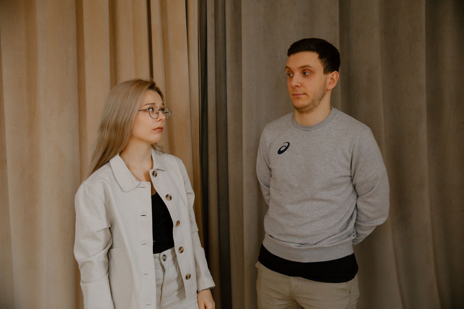 Homem e mulher se olhando ao lado de uma cortina