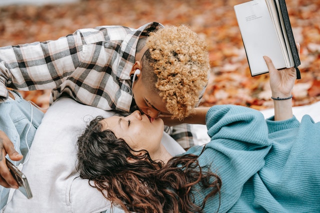 Mulher negra e mulher branca se beijando.