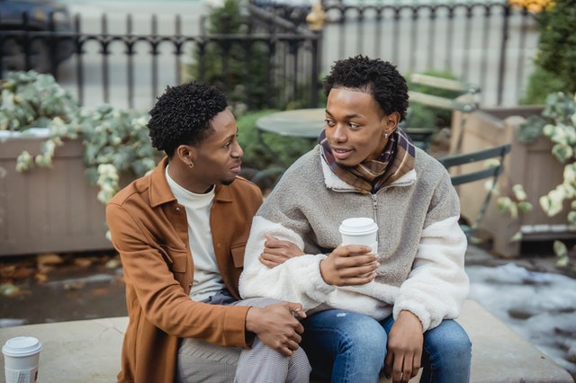 Homens negros com os braços entrelaçados conversando.