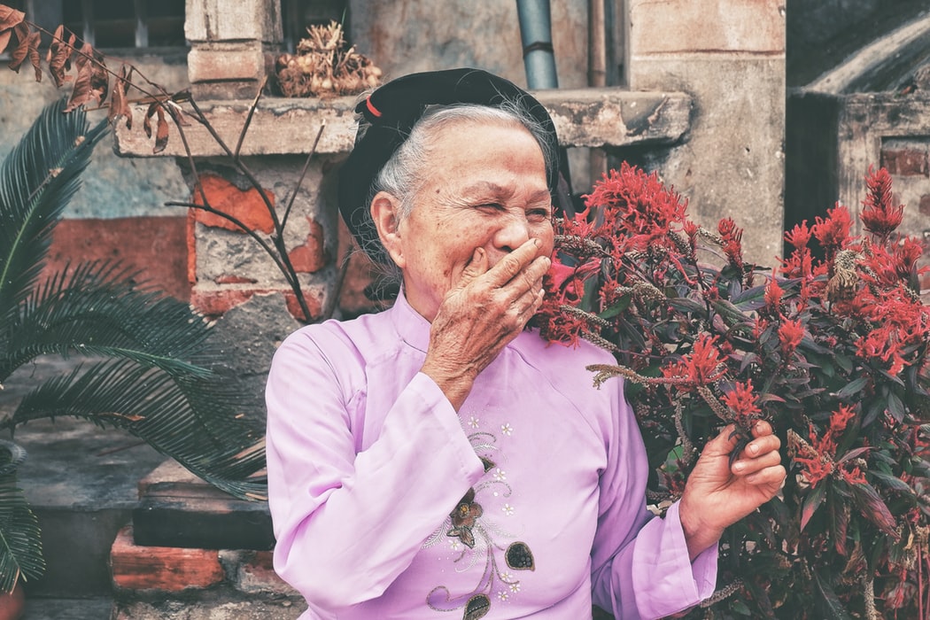 Mulher sorrindo ao lado de uma planta com flores