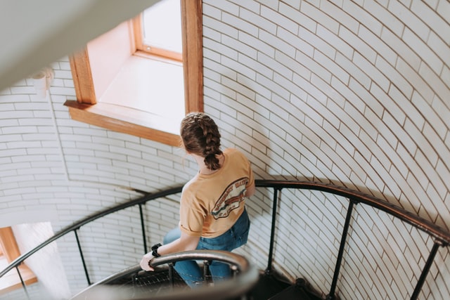 Mulher descendo escada espiral.