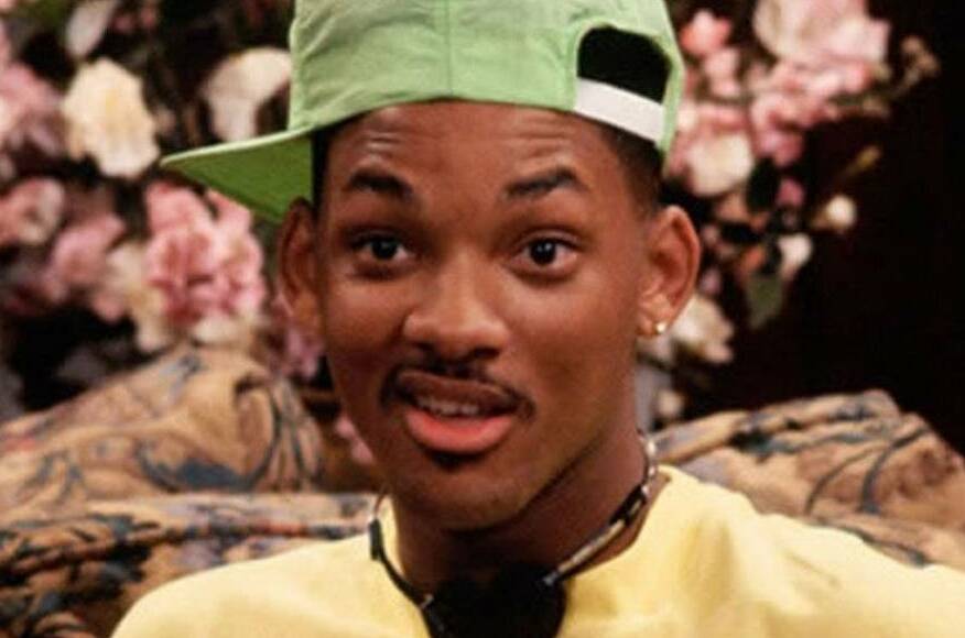 Homem negro usando boné verde e camiseta amarela.