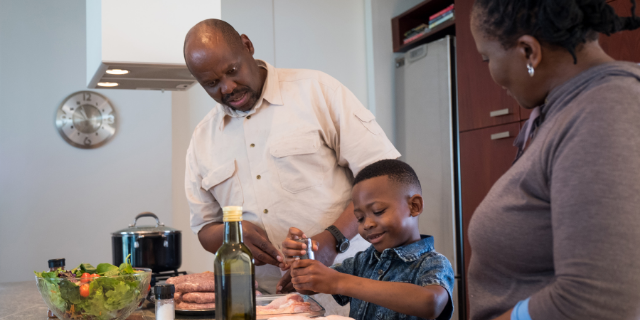 Avós cozinham com neto. 