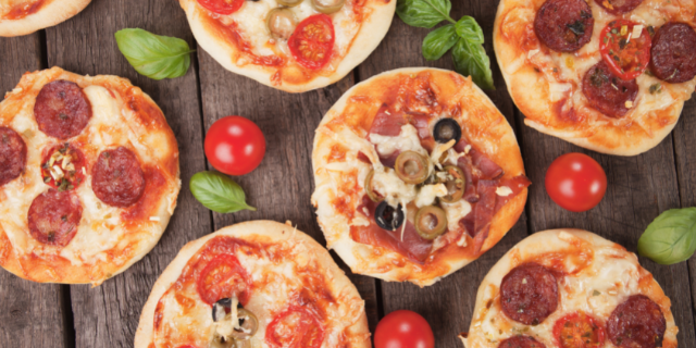 Pizzas pequenas sobre superfície madeira escura. 