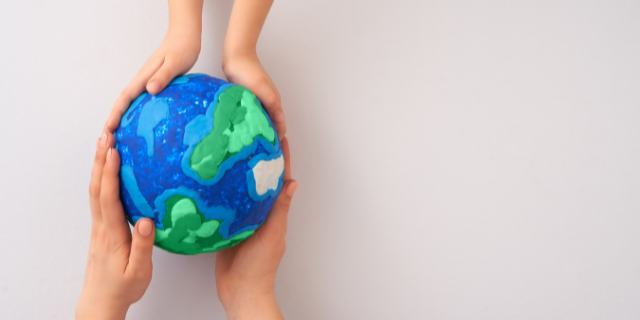 Mãos seguram globo terrestre artesanal. 