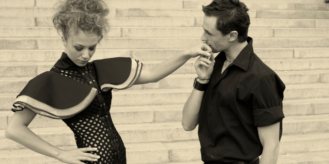 Homem beija a mão de mulher que está cabisbaixa e parece negá-lo.