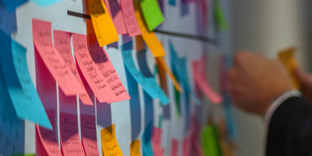 Homem organiza post-its em um painel branco.