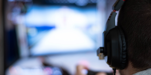 Dzonsli / Canva Homem com fones de ouvido em frente a computador.