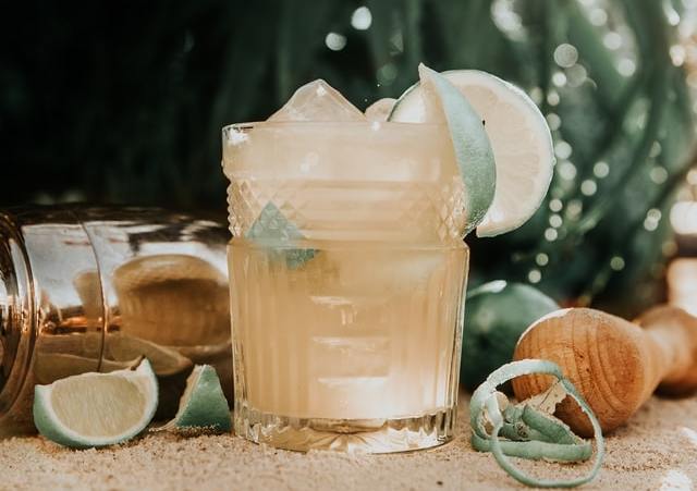 Caipirinha de limão num copo transparente e rodelas de limão na borda.