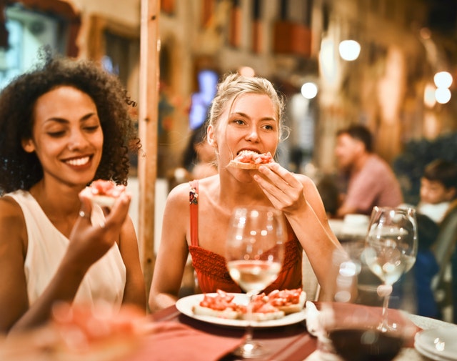 Duas mulheres em um restaurante comendo pizza.