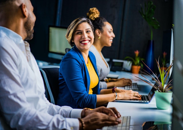 Homem e mulher em ambiente de trabalho, sorrindo um para o outro