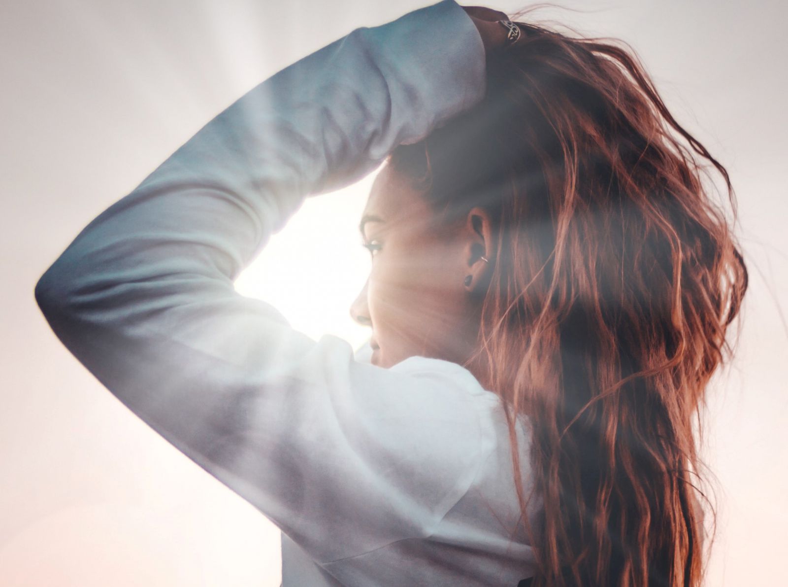 Mulher com mãos nos cabelos de lado com luz refletindo