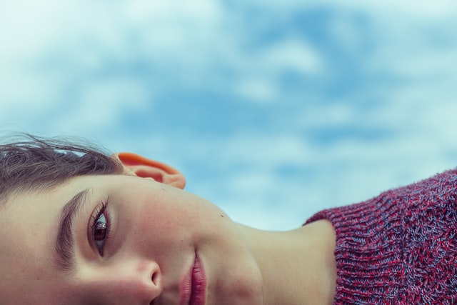 Meio rosto de pessoa branca deitada.